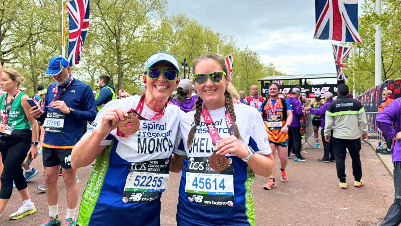 Photo showing two Spinal Research fundraisers holding their medals after completing London Marathon.