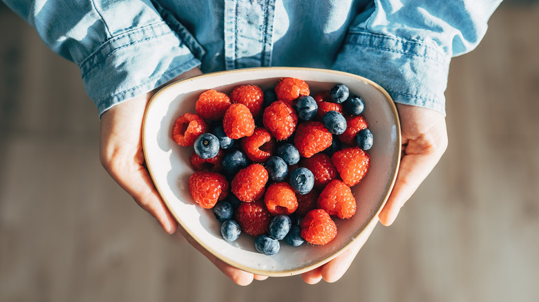 Hands holding a bowl of berries