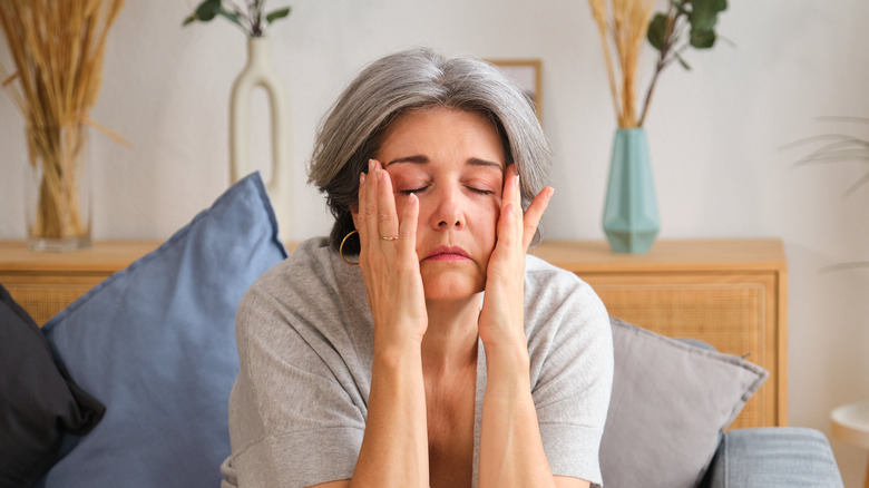 over 50 woman sitting on couch with hands on face