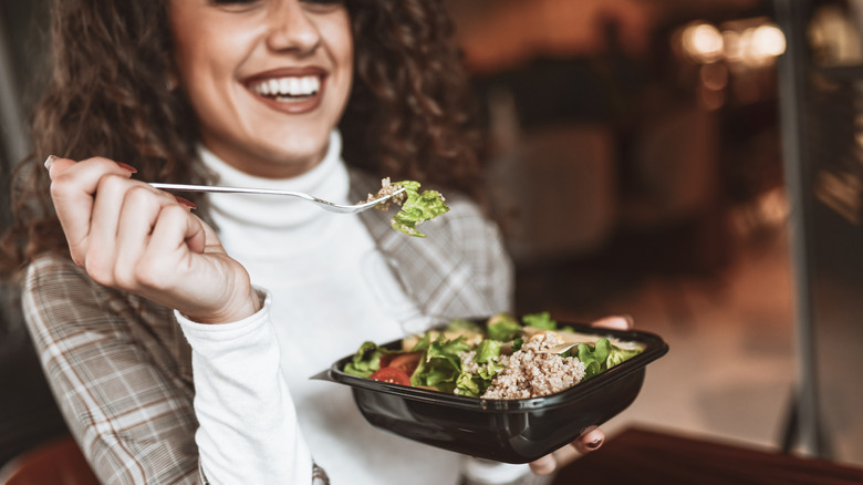 A woman eating a salad topped with tuna