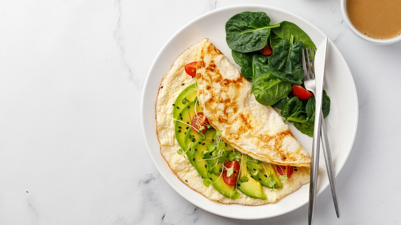 egg white omelet stuffed with avocado and tomatoes with a side of greens