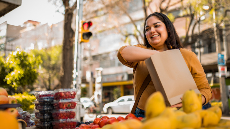 happy woman choosing fruit at farmer's market stand