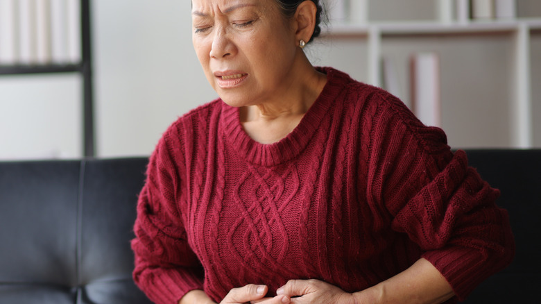 woman experiencing nausea while sitting on sofa