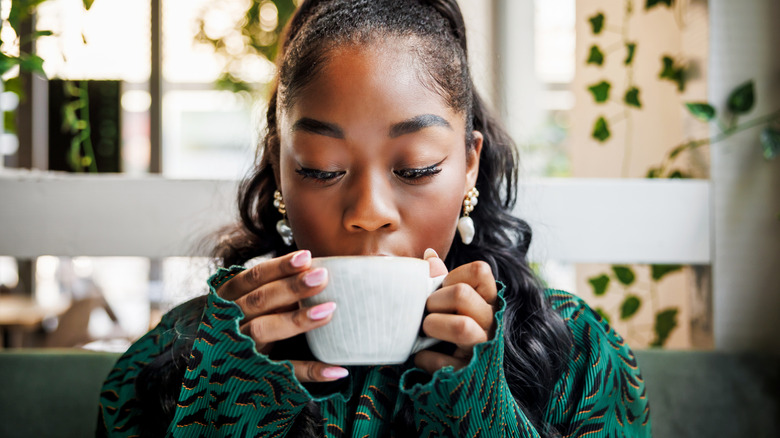 A woman sipping a cup of a hot beverage