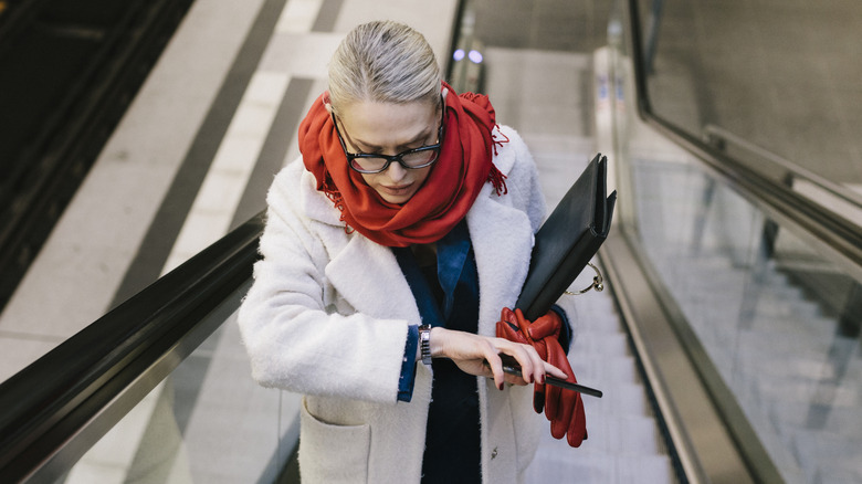 A woman checking her watch as she ascends an escalator