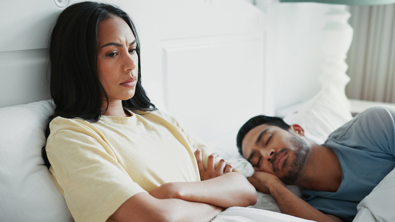 angry woman sitting next to sleeping man