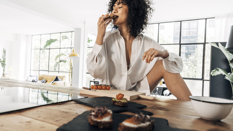 A person eating bread with tomatoes on it