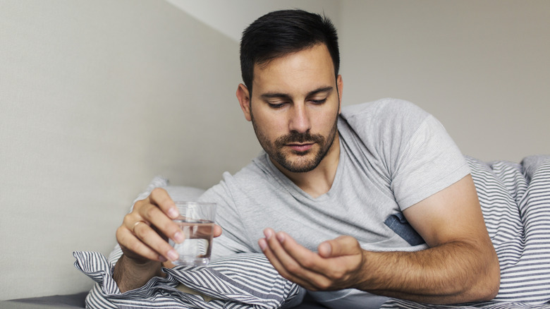 A man lying in bed holding a glass of water