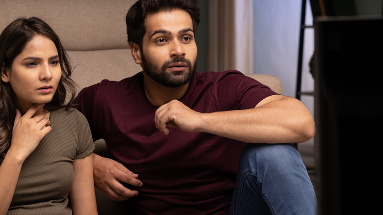 A couple watching television at home in front of the couch