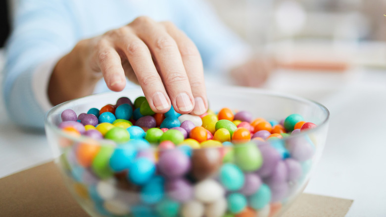 A woman's hand reaching into a dish of candies