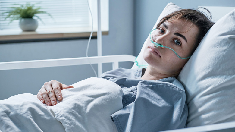 A sick woman on a hospital bed with oxygen tube