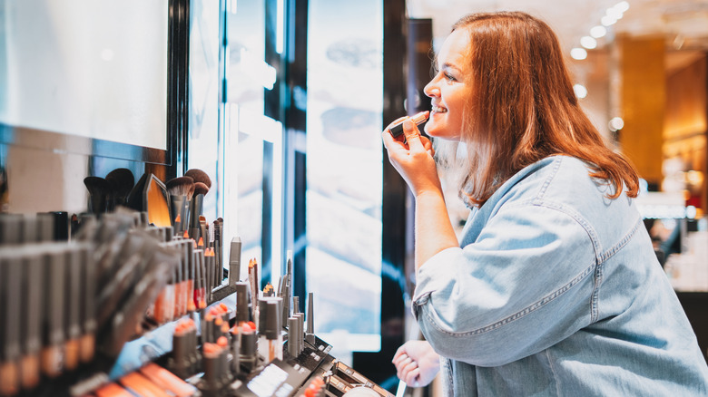 woman applying lip gloss at a store