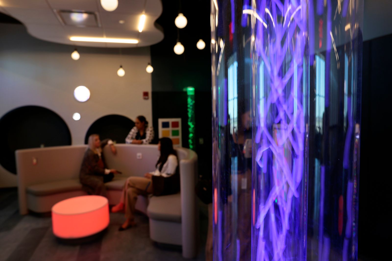 purple column of light in foreground to right circular seating area in background to left glowing soft red table...
