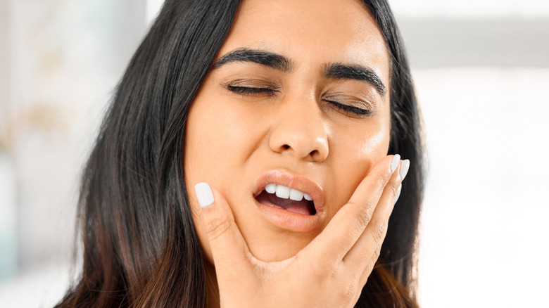 woman holding face in pain