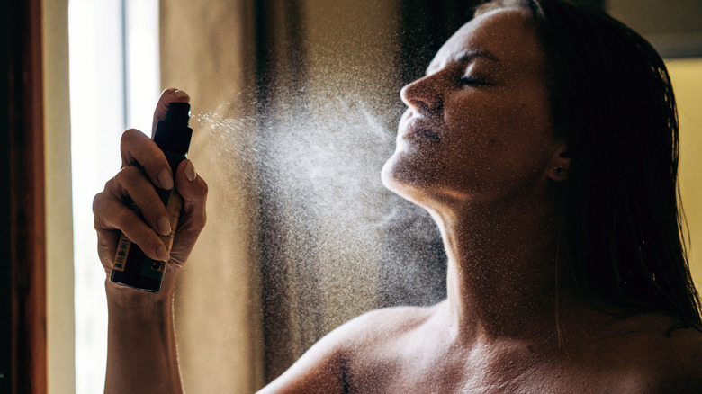 A woman spraying oil on her neck area