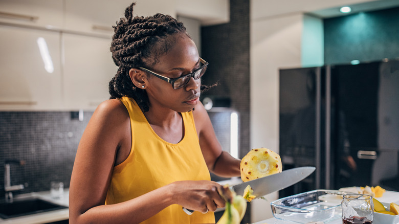 Woman cutting pineapple in her kitchen