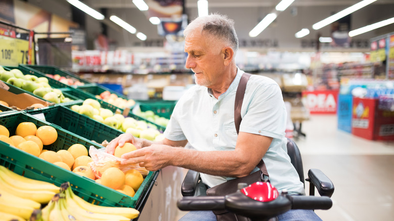 older man shopping for produce while using a wheelchair