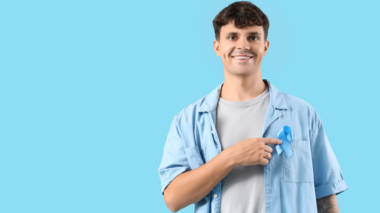 Young man pointing towards prostate cancer ribbon pinned on his shirt