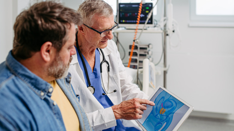 Doctor using digital image to explain stage 2 prostate cancer to male patient