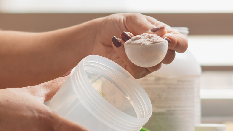 A woman's hand scooping creatine powder