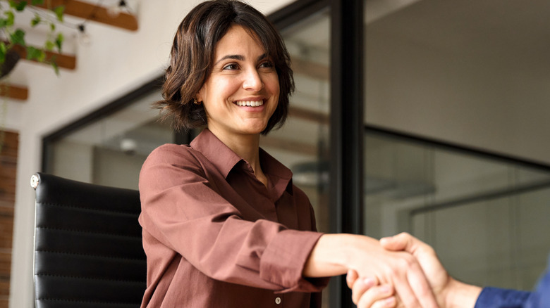 A woman smiling while shaking hands