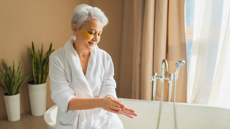 An older woman applying lotion on her hands