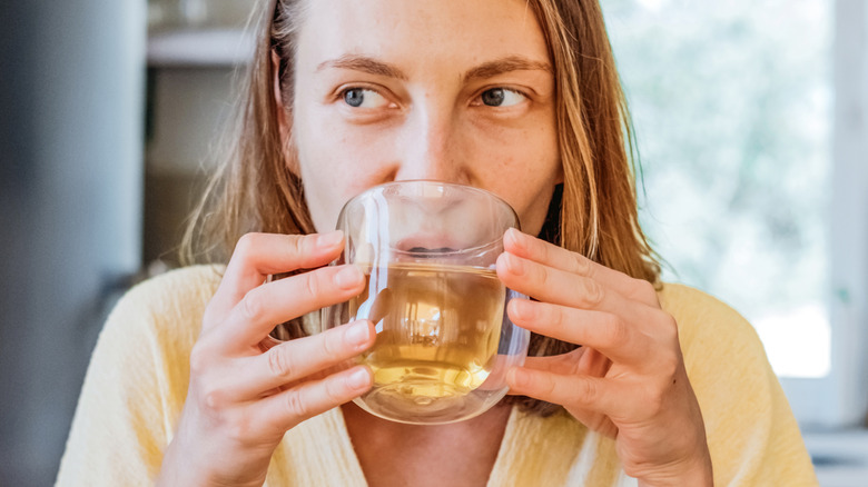 A woman drinking a cup of yellow tea