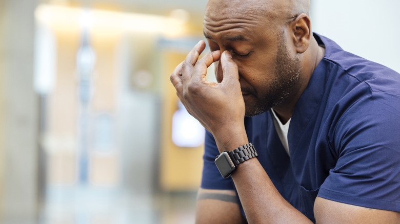 man pinching nose and looking unwell