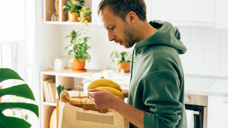 man looking at bunch of bananas in kitchen