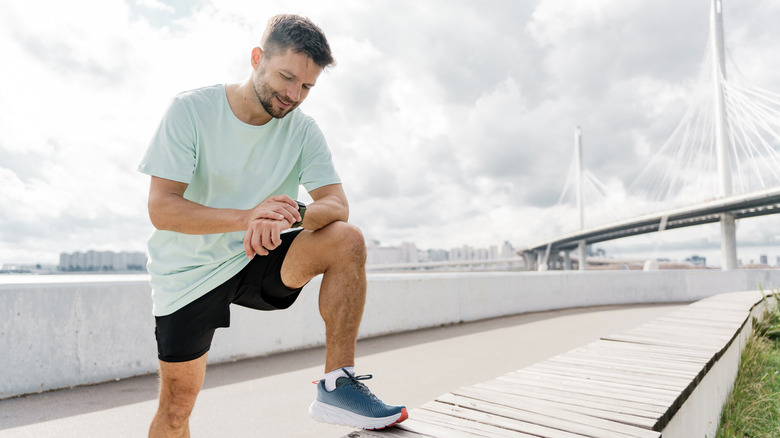 A man looking at his watch before starting a run