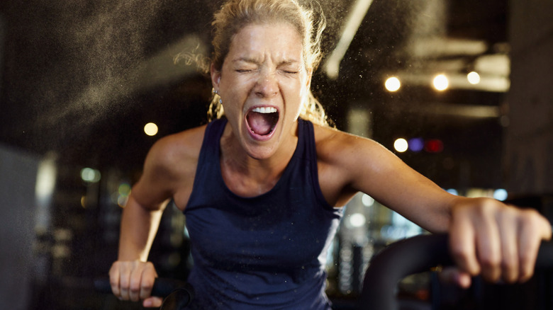 A woman grimacing during an indoor cycling class
