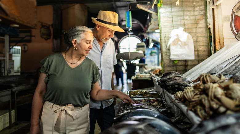 older couple buying fish at a market